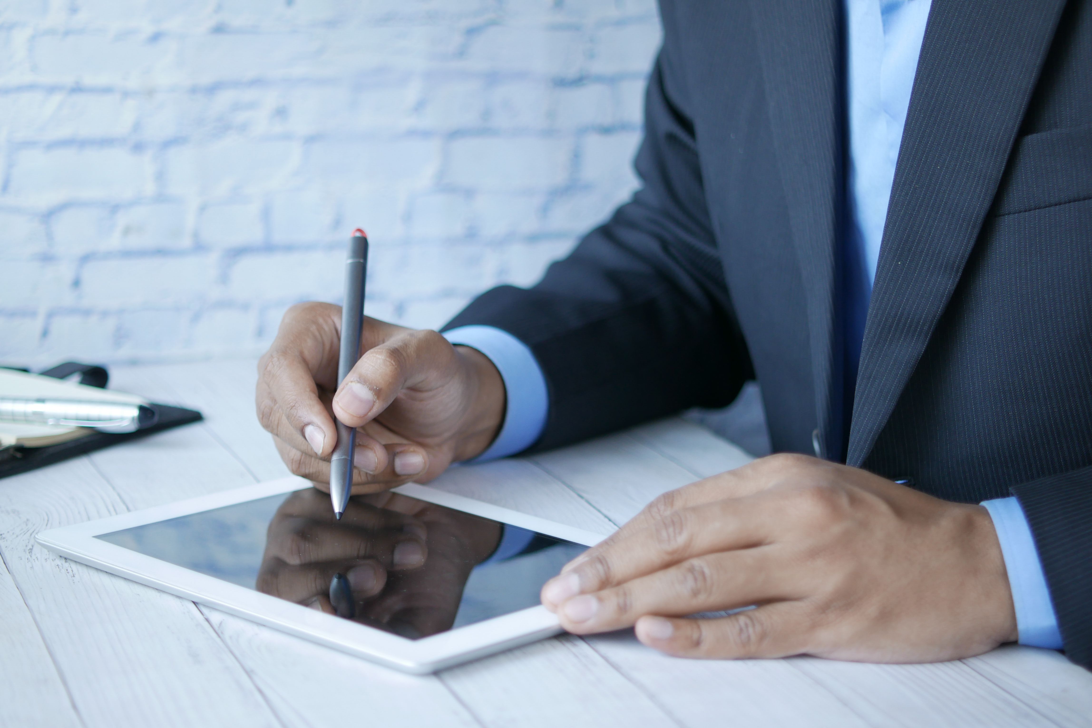 Personne signant un document en ligne sur tablette, bureau moderne, lumière naturelle
