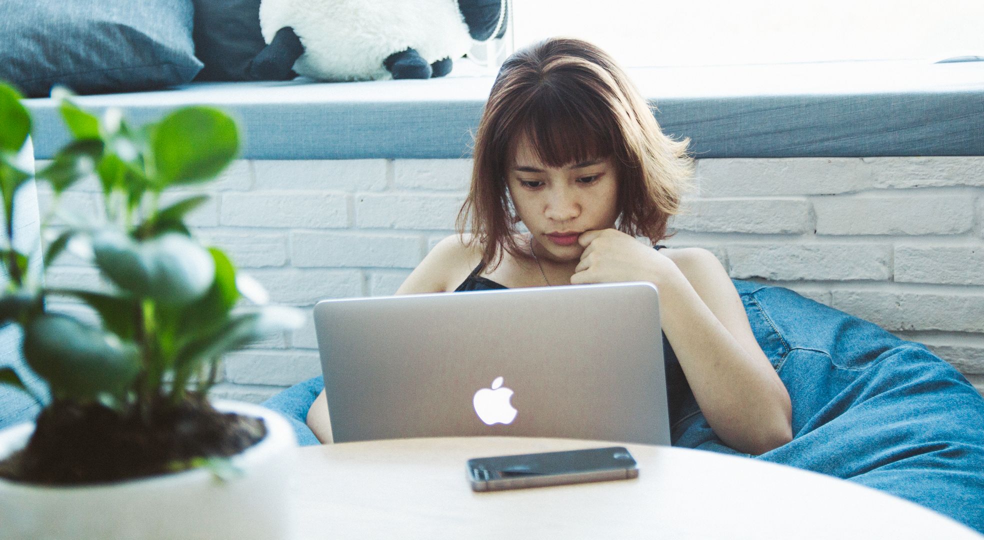 Freelance consultant travaillant sur ordinateur portable dans un espace de coworking moderne, documents contractuels sur écran